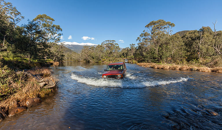 Red 4WD vehicle crosses the Swampy Plain River, Kosciuszko National Park. Photo: Murray Vanderveer/OEH