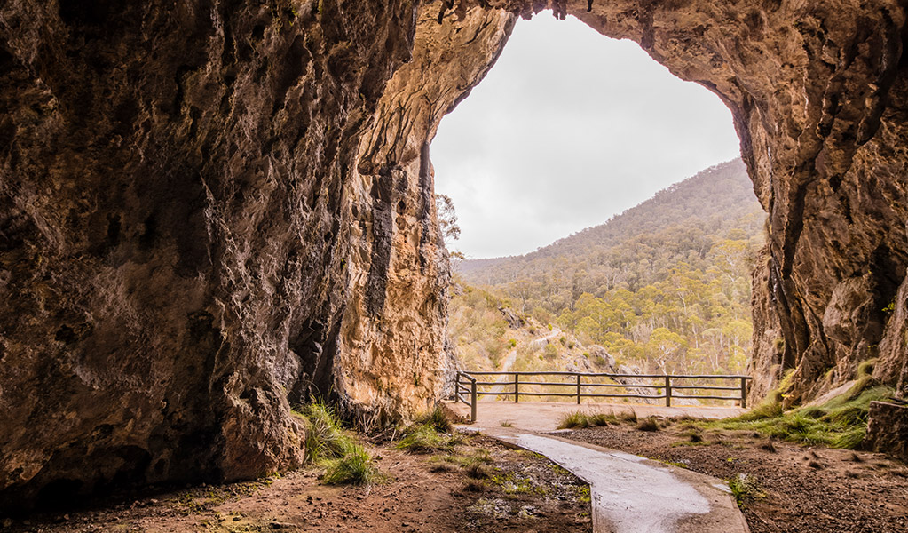 Looking outside North Glory Cave entrance from inside the cave with Kosciuszko National Park in the distance. Credit: Murray Vanderveer &copy; DCCEEW