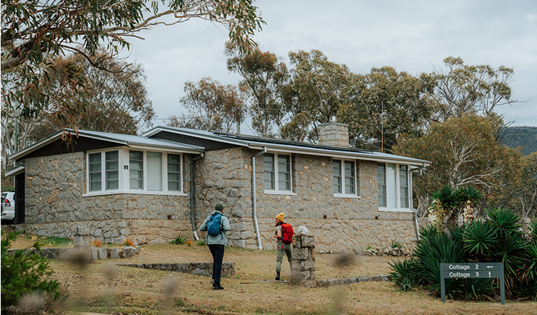 2 hikers standing outside a cottage at Creel Bay near Snowies Alpine Walk. Credit: Remy Brand / DCCEEW © Caravel Content