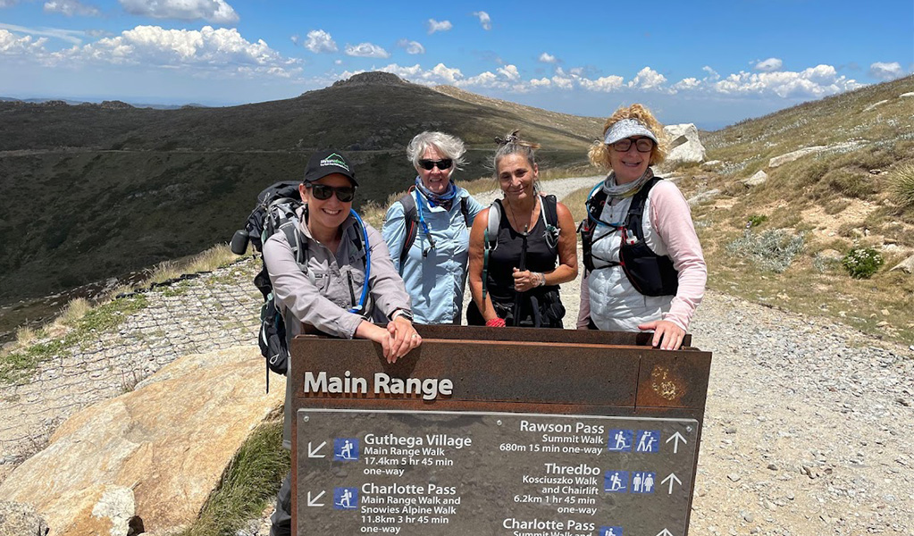 People on a multi-day tour with Life's An Adventure posing with the Main Range interpretive sign along Snowies Alpine Walk. Credit: Life's An Adventure