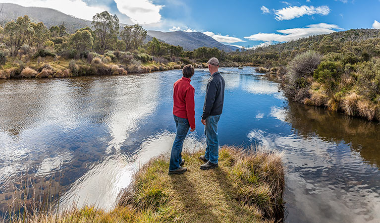 A man and woman stand beside the Thredbo River near Bullocks Hut, Kosciuszko National Park. Photo: Murray Vanderveer/DPIE