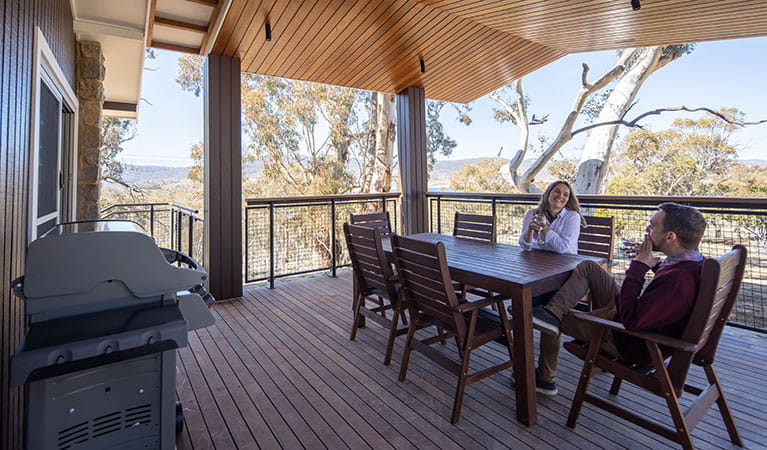 A couple on the deck of one of Creel Bay cottages with trees and mountains in the background. Photo &copy; Murray Vanderveer