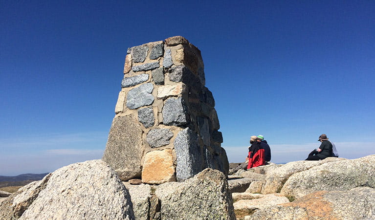 Walkers rest by the trig at the summit of Mount Kosciuszko. Photo: Elinor Sheargold