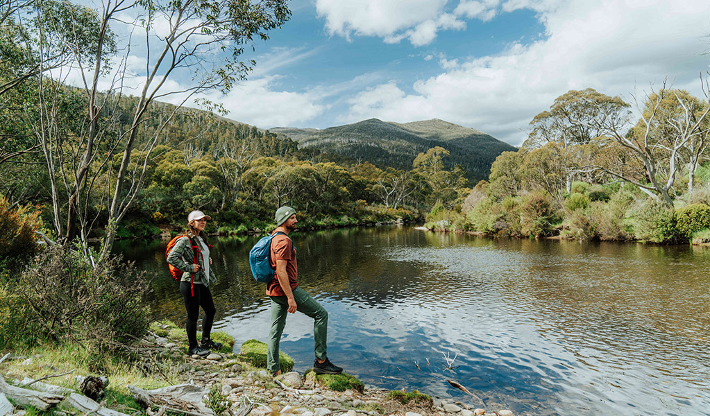 2 hikers taking in the serenity of Thredbo river on Perisher Valley to Bullocks Flat walk. Credit: Remy Brand / DCCEEW &copy; Caravel Content