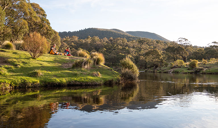 Two men sit beside the Thredbo River near Thredbo Diggings campground, Kosciuszko National Park. Photo: Robert Mulally/DPIE