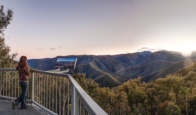 A woman stands next to a sign at Black Perry lookout, Kosciuszko National Park. Photo: Murray Vanderveer/OEH