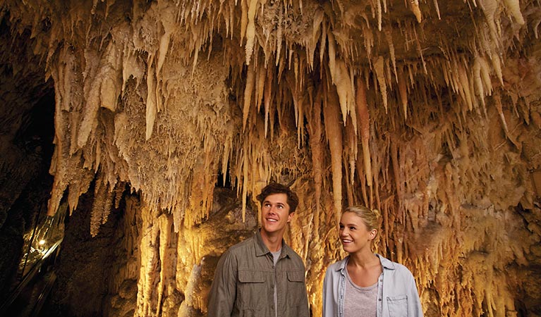 A couple tour Jillabenan Cave, Yarrangobilly Caves, Kosciuszko National Park. Photo: Destination NSW
