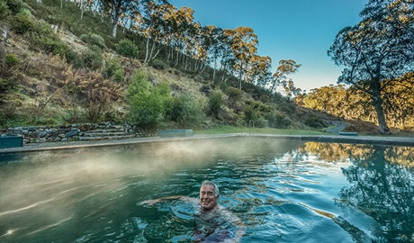 A man relaxes in the steaming waters of Yarrangobilly Caves thermal pool, in Kosciuszko National Park. Photo: Murray Vanderveer/DPIE.