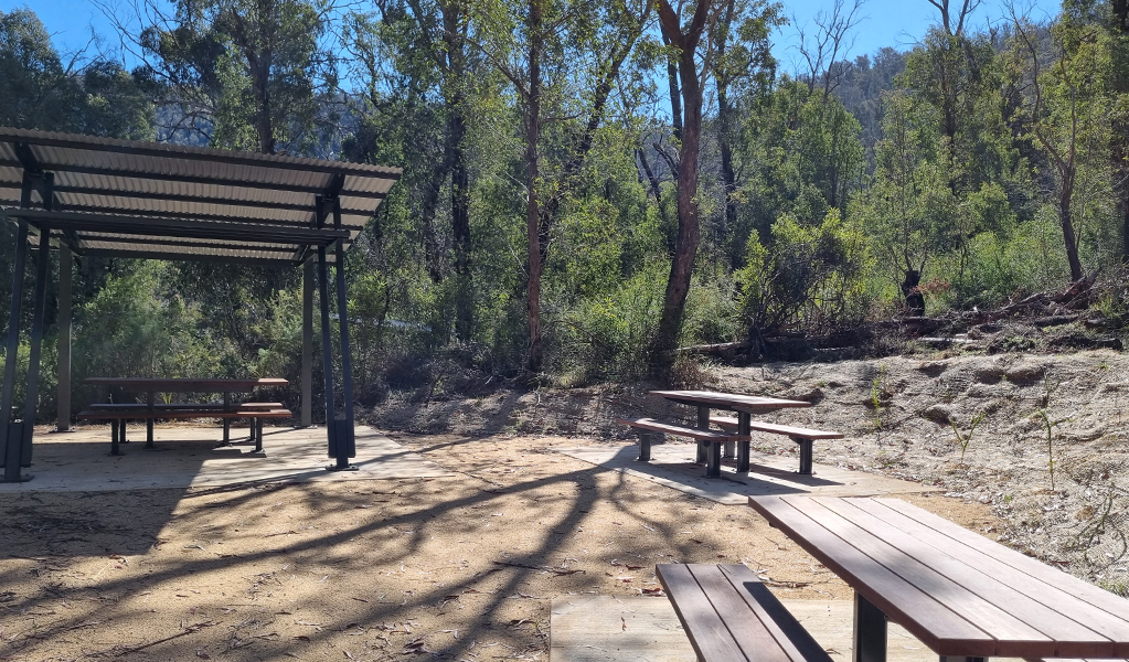 Open and shaded picnic tables at the picnic area surrounding Yarrangobilly Caves thermal pool. Credit: Paul Sims &copy; DCCEEW