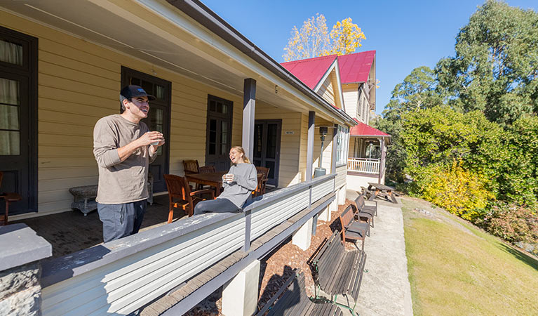 A couple on the verandah at Yarrangobilly Caves House 1901 section, Kosciuszko National Park. Photo: Boen Ferguson/OEH.