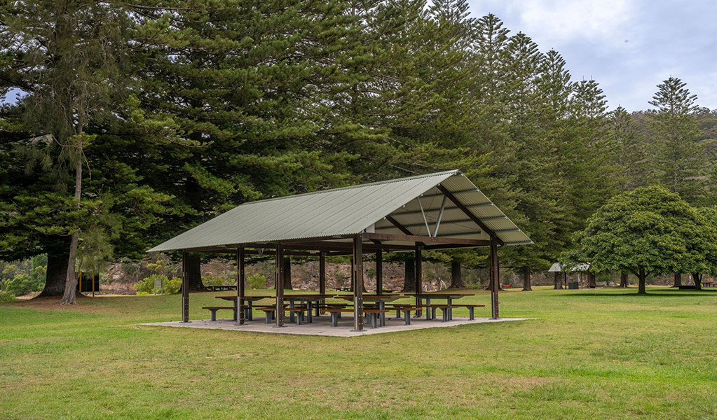 A group of picnic benches under a shelter surrounded by an open grassy picnic area. Credit: John Spencer/DCCEEW  &copy; DCCEEW