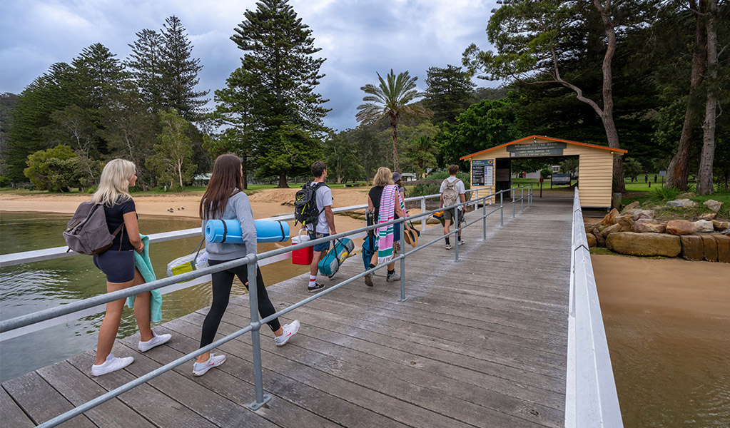 Campers walking across the ferry wharf, arriving at The Basin campground. Credit: John Spencer/DCCEEW  &copy; DCCEEW