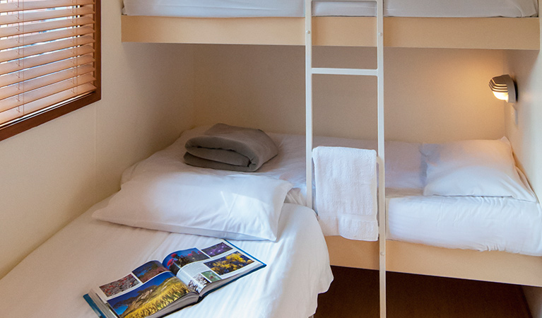 Bedroom with bunk beds and a single bed at Lane Cove cabins, Lane Cove National Park. Photo: Bob Fowler/OEH