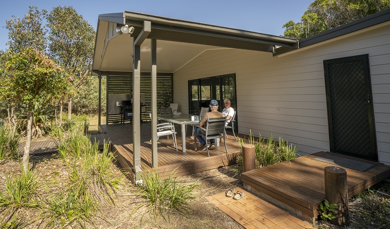 2 people sitting down at the table in the outdoor dining area at Plomer Beach House, Limeburners Creek National Park. Photo: John Spencer/OEH