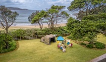 Man sitting beside his tent looking out at the ocean, at Limeburners Creek National Park. Photo: John Spencer/OEH