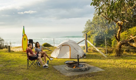 A couple relaxes near their tent and surfboards at Gillards campground in Mimosa Rocks National Park. Photo: Tim Clark/DNSW