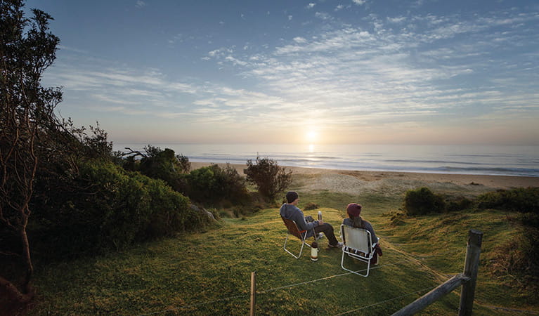 A couple watching the sunrise at Gillards campground, Mimosa Rocks National Park. Photo: David Finnegan/DPIE