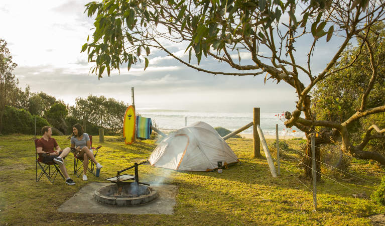 A couple relaxes beside the campfire at Gillards campground in Mimosa Rocks National Park. Photo: Tim Clark/DNSW