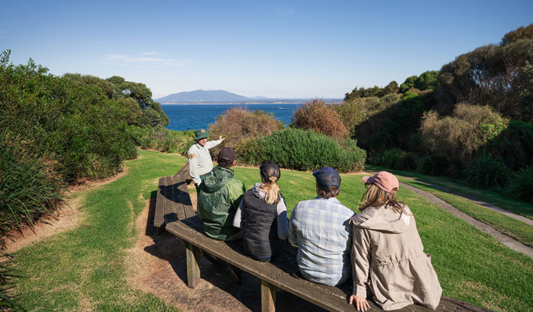 A ranger guide talks to 4 people sitting on a bench at  Barunguba Montague Island Nature Reserve. Photo &copy; Daniel Tran