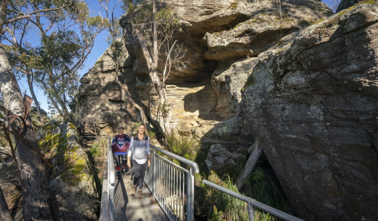 Two people walk through sandstone rock formations on Pigeon House Mountain Didthul walking track. Photo: John Spencer