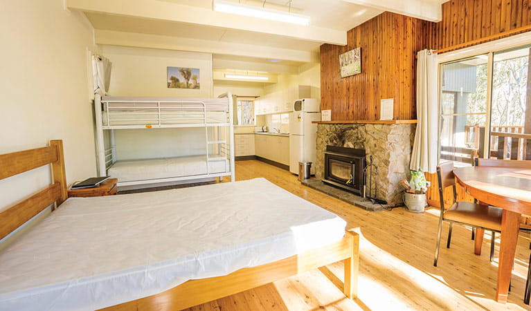 Interior of Manning cabin with beds, dining and woodfire. Photo: Simone Cottrell/OEH