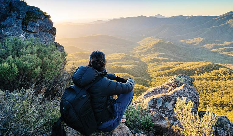 Woman crouching on rock enjoying sunset views from The Governor lookout walking track. Photo: Simone Cottrell &copy; OEH