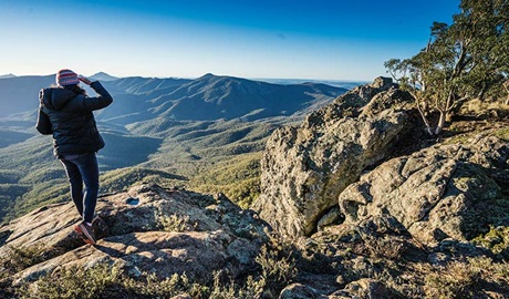 Woman standing on rocks enjoying the views of the Nandewar wilderness. Photo: Simone Cottrell &copy; OEH