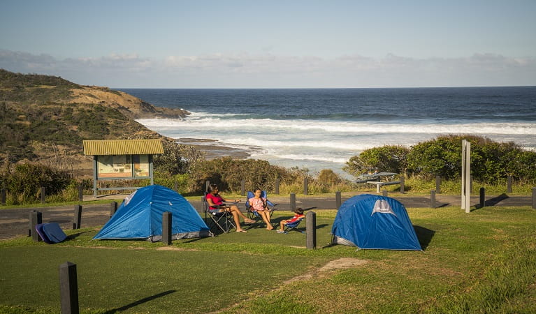Family sitting beside their tents at Frazer campground, Munmorah State Conservation Area. Photo: John Spencer/OEH