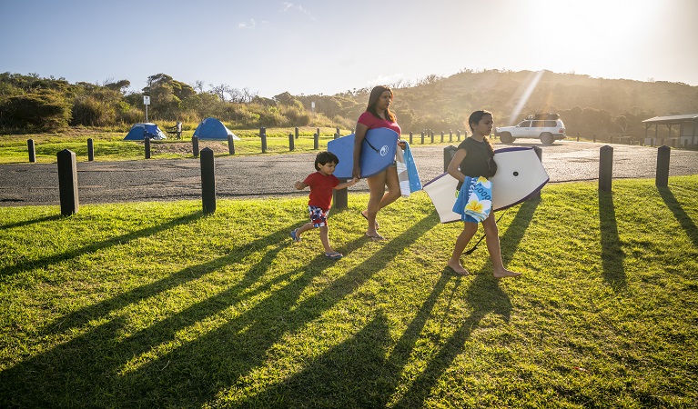 Family walking to Frazer beach with their swimming gear at Frazer campground, Munmorah State Conservation Area. Photo: John Spencer/OEH