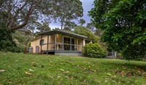 Exterior of one of the Depot Beach cabins, surrounded by trees in Murramarang National Park. Photo: John Spencer &copy; DPIE