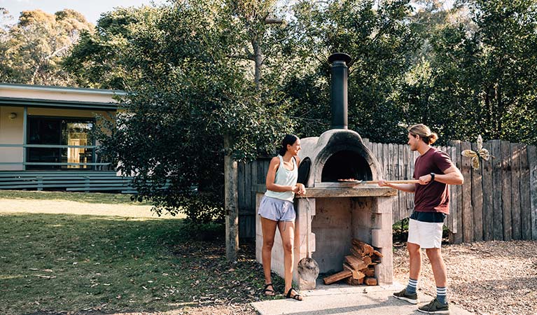 A couple cook a barbecue at Depot Beach cabins, Murramarang National Park. Photo: Melissa Findley/OEH.