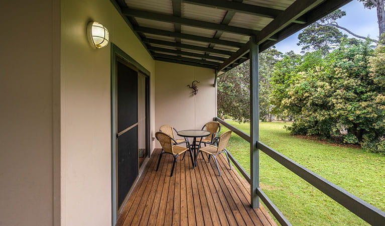 The verandah at one of the Depot Beach cabins, with outdoor table setting in Murramarang National Park. Photo: John Spencer &copy; DPIE