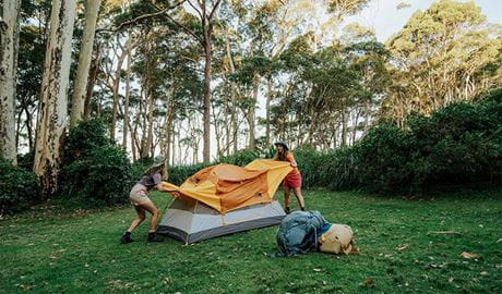 2 campers setting up their tent on grass at Depot Beach campground, Murramarang National Park. Credit: Remy Brand &copy; Remy Brand