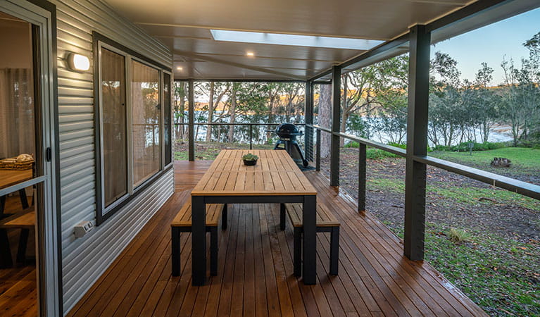 Judges House covered verandah with dining table, seating and a water view, Murramarang National Park. Photo: John Spencer &copy;DPIE