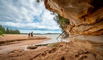 2 people walking past a sandstone rock feature near Wasp Head. Credit: John Spencer &copy; DPE