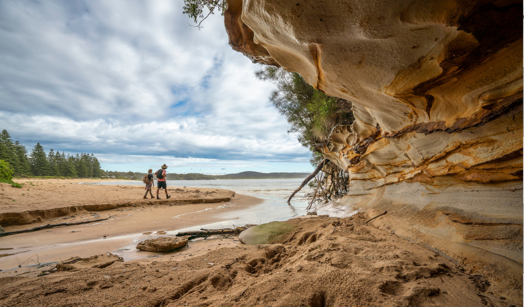 2 people walking past a sandstone rock feature on the Murramarang South Coast Walk. Credit: John Spencer © DPE