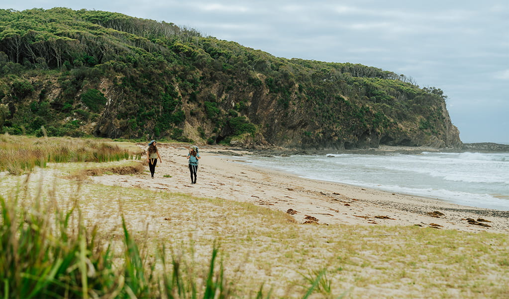 2 bushwalkers walking along the sand of Oaky Beach, Murramarang National Park. Credit: Remy Brand &copy; Remy Brand