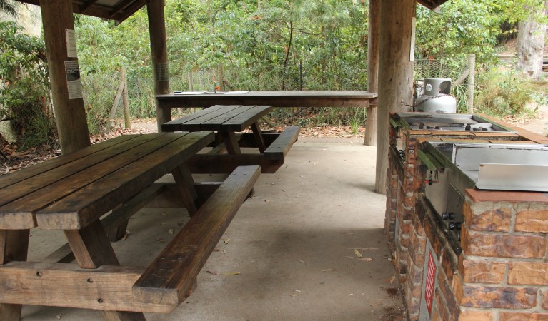 Barbecues and picnic tables under a shelter at Pebbly Beach picnic area, Murramarang National Park. Photo: John Yurasek &copy; OEH