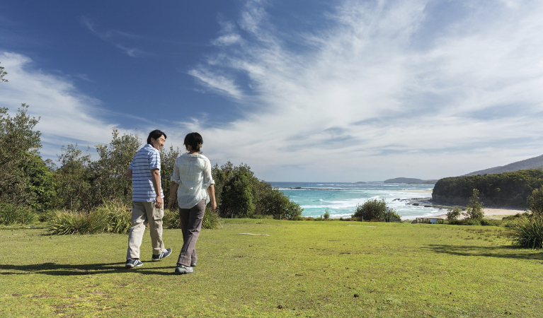 Couple walking at Pretty Beach picnic area in Murramarang National Park. Photo credit: David Finnegan. &copy;DPIE