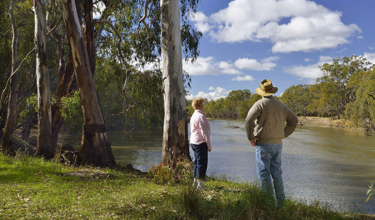 View of the Murrumbidgee River, with a woman and man in the foreground standing on the river bank. Photo: Gavin Hansford/OEH.