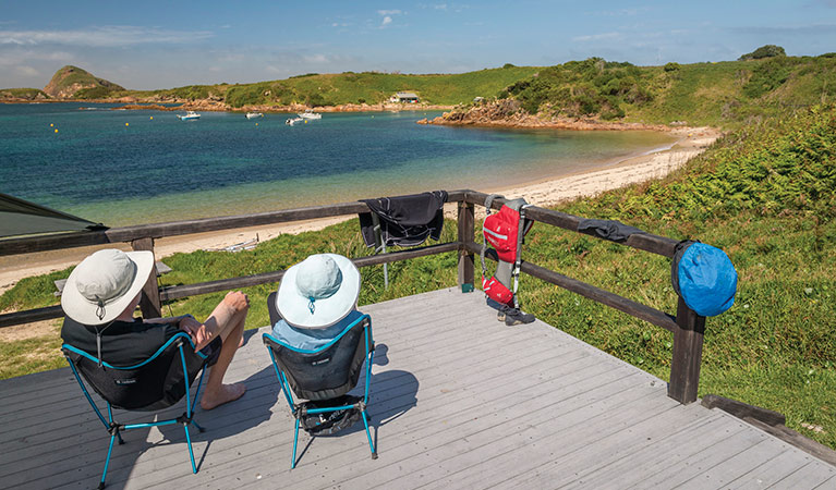 2 people enjoying the view on the camping platform at Broughton Island campground, Myall Lakes National Park. Photo: John Spencer/OEH