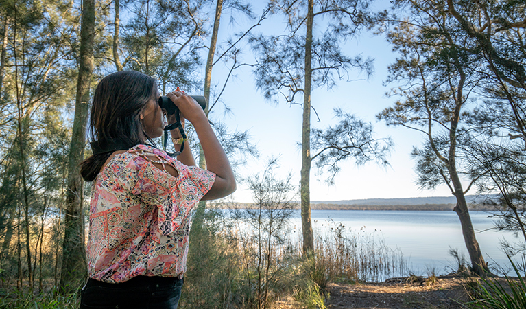 Camper looking out over Boolambayte Lake, Bungarie Bay campground. Photo: John Spencer/OEH