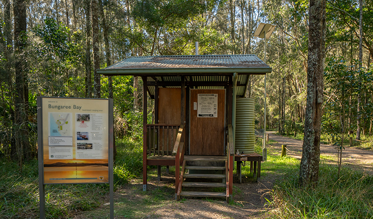 Lady reviewing the sign at Bungarie Bay campground. Photo: John Spencer/OEH