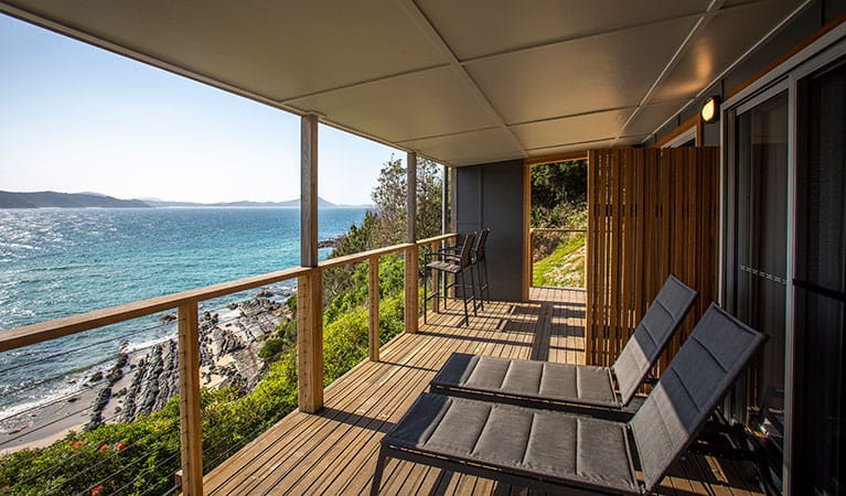 Sun lounges on the balcony of Davies Cottage overlooking Boat Beach and Sugarloaf Bay. Photo: John Spencer &copy; DPIE