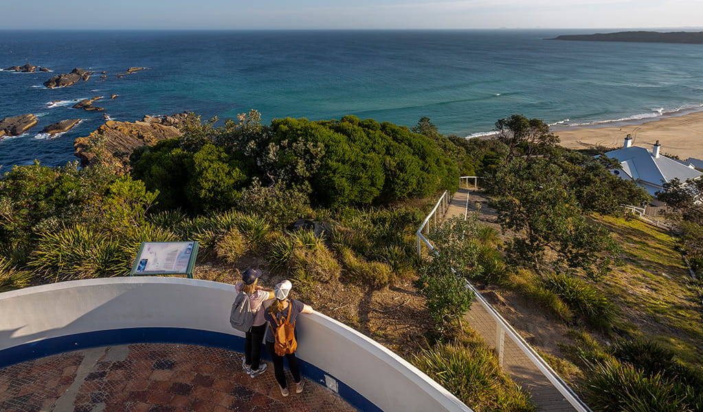An aerial photo of 2 visitors looking at the ocean views from Sugarloaf Point Lighthouse, Myall Lakes National Park. Credit: Brent Mail &copy; DPE
