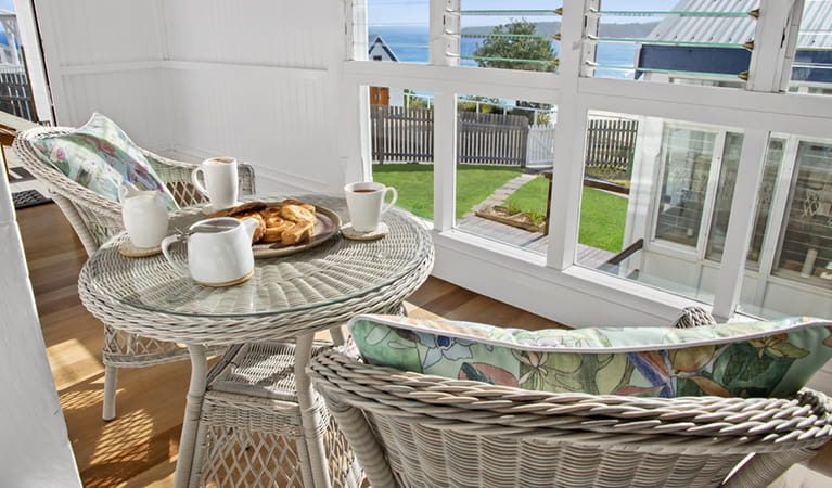 Assistant Keeper's cottage breezeway with chairs and table looking out over the ocean. Photo: Seal Rocks Lighthouse Cottages 