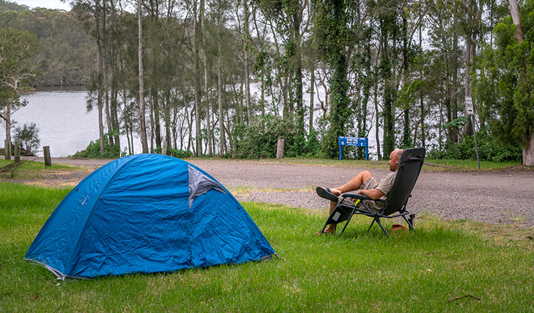 A man sitting by his tent at Violet Hill campground and picnic area in Myall Lakes National Park. Photo: John Spencer &copy; DPIE