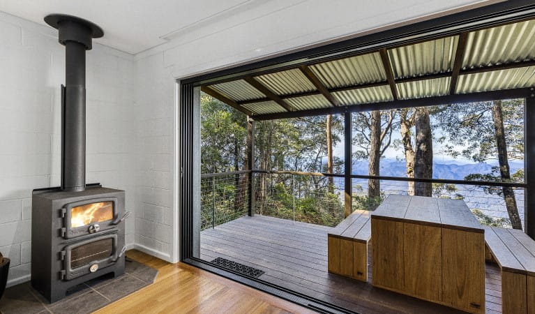 The indoor fireplace and view of the deck at The Chalet in New England National Park. Photo: Mitchell Franzi &copy; DPIE