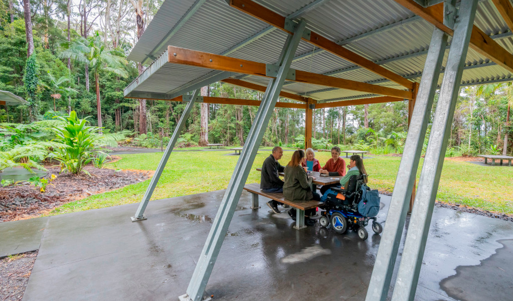 Visitors sitting at a picnic shelter at Minyon Falls picnic area in Nightcap National Park. Credit: John Spencer &copy; DPE