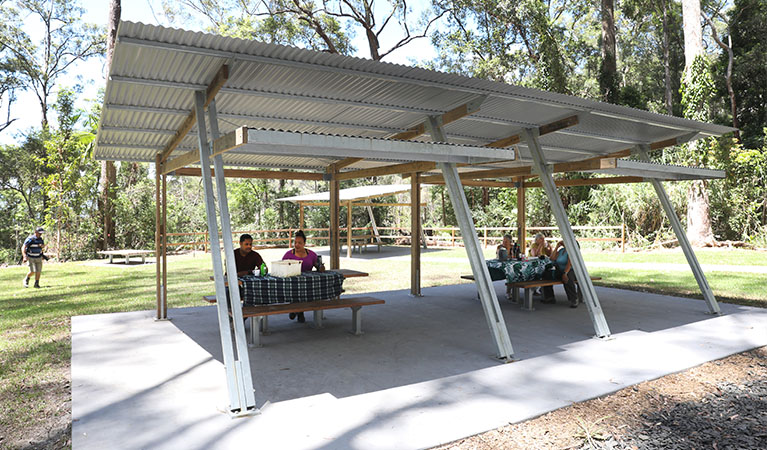 Visitors sitting at sheltered picnic tables at Minyon Falls lookout. Photo: Jimmy Malecki &copy; DPE
